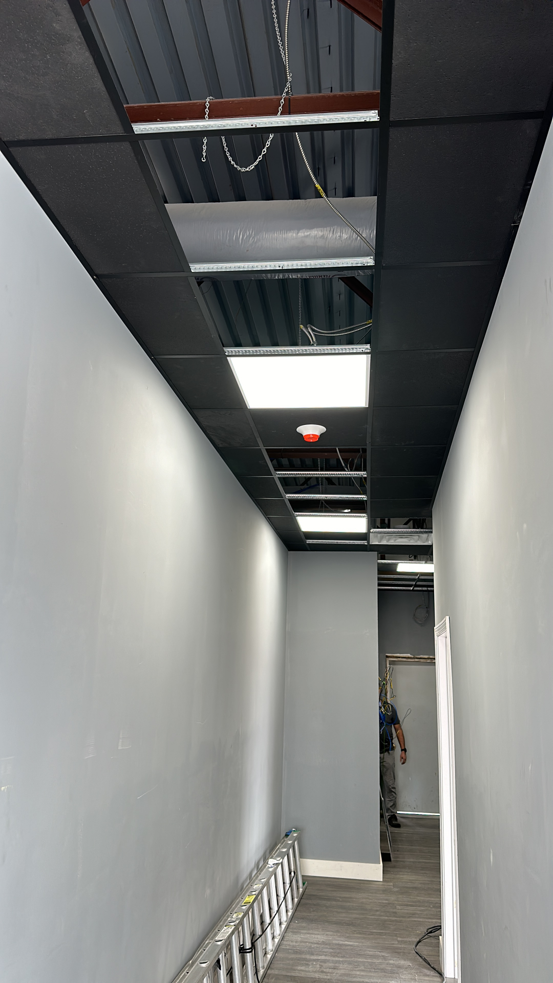 Commercial corridor with grid ceiling and recessed LED panel lighting